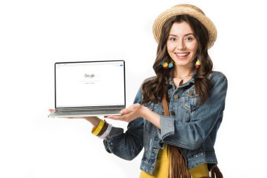 Kiev, Ukrayna - 4 Şubat 2019: beyaz izole ekranda google web sitesi ile dizüstü bilgisayar tutan hasır şapka gülümseyen hippi kız