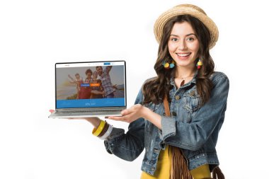 Kiev, Ukrayna - 4 Şubat 2019: beyaz izole ekranda couchsurfing web sitesi ile dizüstü bilgisayar tutan hasır şapka gülümseyen hippi kız