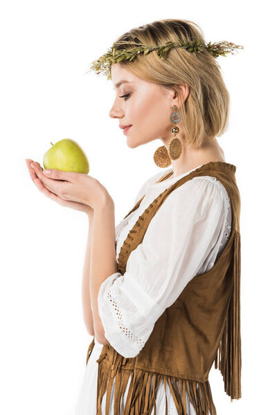 вид сбоку очаровательной девушки хиппи, держащей в руках зеленое яблоко, изолированное от белого
