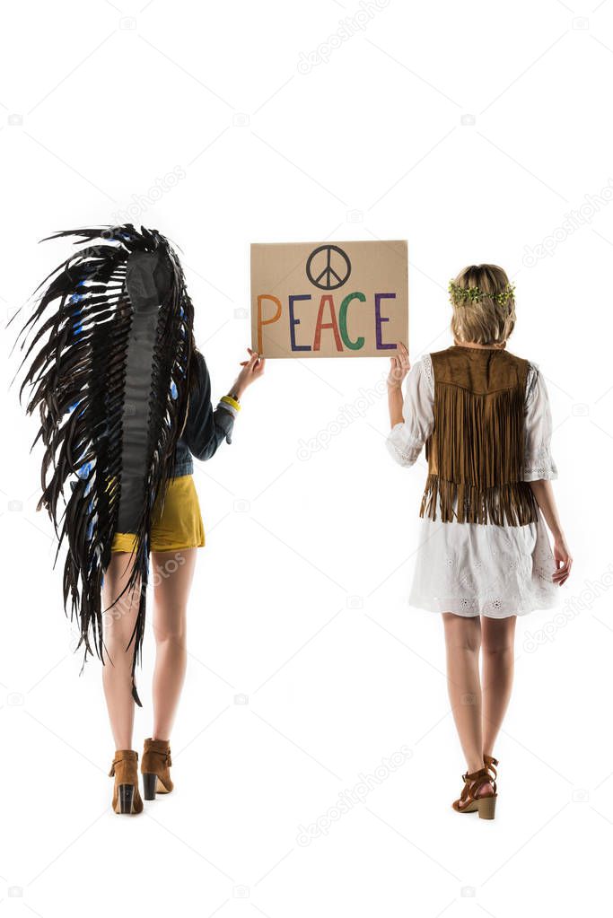 back view of two bisexual hippie girls in indian headdress and wreath holding placard with inscription isolated on white