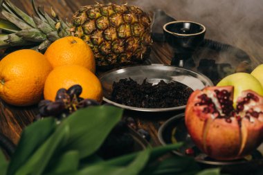 nargile, tütün, elma, üzüm, portakal, garnet ve ahşap yüzeyüzerinde ananas