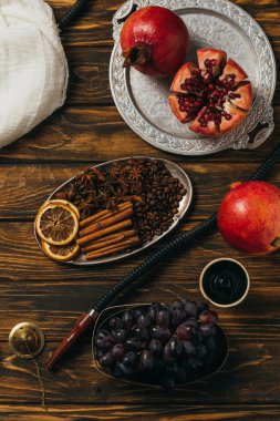 nargile, tarçın, garnet, üzüm ve ahşap yüzeyüzerinde kurutulmuş portakal üst görünümü