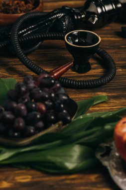 selective focus of grapes and hookah on wooden surface clipart