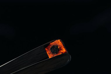 hookah tongs and hot coal isolated on black clipart