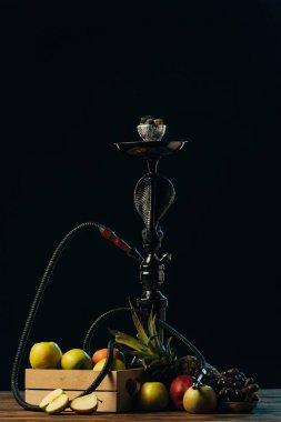 fresh tasty fruits and hookah on wooden surface isolated on black clipart