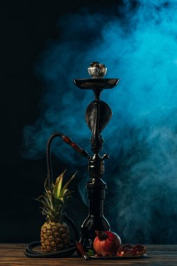 hookah with exotic fruits on wooden surface in blue smoke clipart