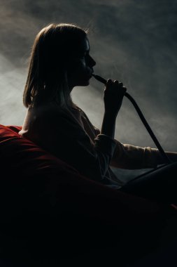 fasulye torbası sandalyede oturan ve karanlıkta nargile içen kadının silueti