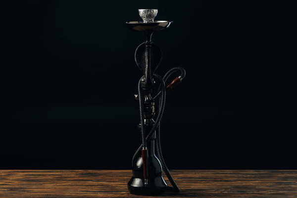 черный кальянный стебель и шланг на деревянной поверхности на черном
