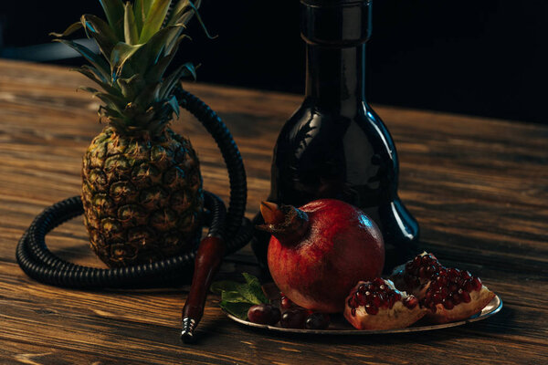 Свежие вкусные фрукты и кальян на деревянной поверхности изолированы на черном
