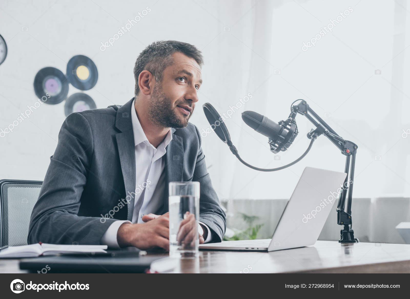 Smiling Radio Host Speaking Microphone While Sitting Laptop Broadcasting Studio Stock Photo by