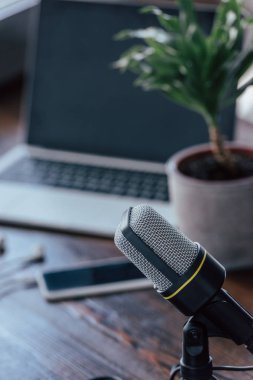 selective focus of microphone near laptop and smartphone with blank screen on wooden table clipart