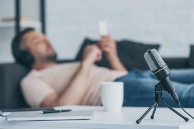 kanepede yatan ve akıllı telefon kullanan adamın yanında masaya adam mikrofon seçici odak