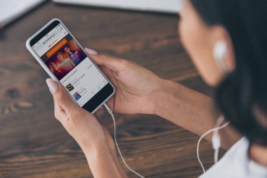 Kiev, Ukrayna - 5 Mayıs 2019: Ekranda Soundcloud uygulaması ile akıllı telefon tutan kulaklıklı kadının kısmi görünümü. 