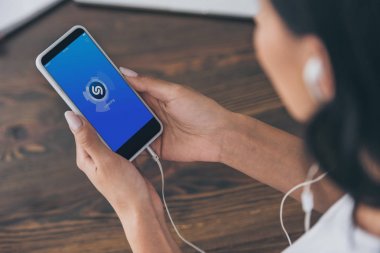 Kiev, Ukrayna - 5 Mayıs 2019: Ekranda Shazam uygulaması ile akıllı telefon tutan genç kadının kırpılmış görünümü.