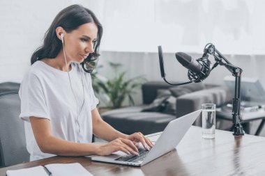 mikrofon yakınında işyerinde otururken dizüstü bilgisayar kullanarak kulaklık güzel radyo host