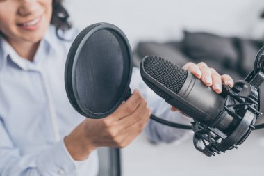 partial view of radio host adjusting microphone in broadcasting studio clipart