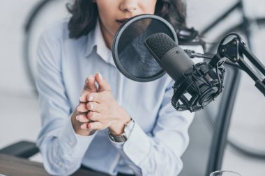 cropped shot of radio host speaking in microphone in broadcasitng studio clipart