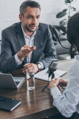 yayın stüdyosunda iş kadını röportaj yaparken yakışıklı radyo sunucusu gesturing