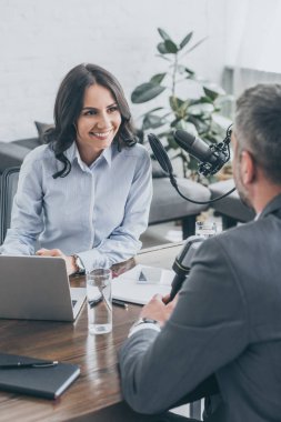 yayın stüdyosunda işadamı ile röportaj yaparken gülümseyen çekici radyo sunucusu