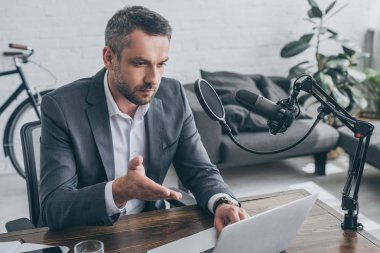 mikrofon yakınında işyerinde otururken dizüstü bilgisayar kullanarak yakışıklı radyo host
