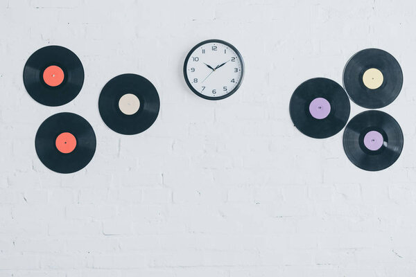 vinyl discs and round clock on white brick wall 