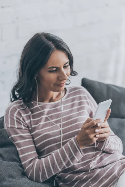 Mujer Sonriente Usando Teléfono Inteligente Mientras Está Sentada Sofá Escuchando — Foto de Stock