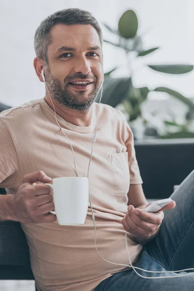 Stilig Man Tittar Kameran Medan Lyssnar Musik Hörlurar Och Håller — Stockfoto