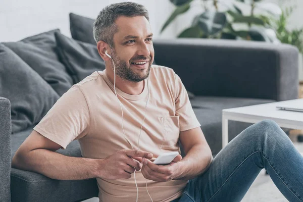 Pohledný Muž Který Poslouchá Hudbu Sluchátkách Dívá Jinam Zatímco Sedí — Stock fotografie