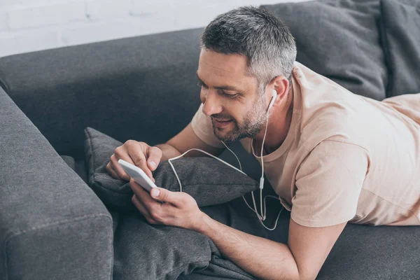 Knappe Man Liggend Bank Luisteren Muziek Koptelefoon Met Behulp Van — Stockfoto