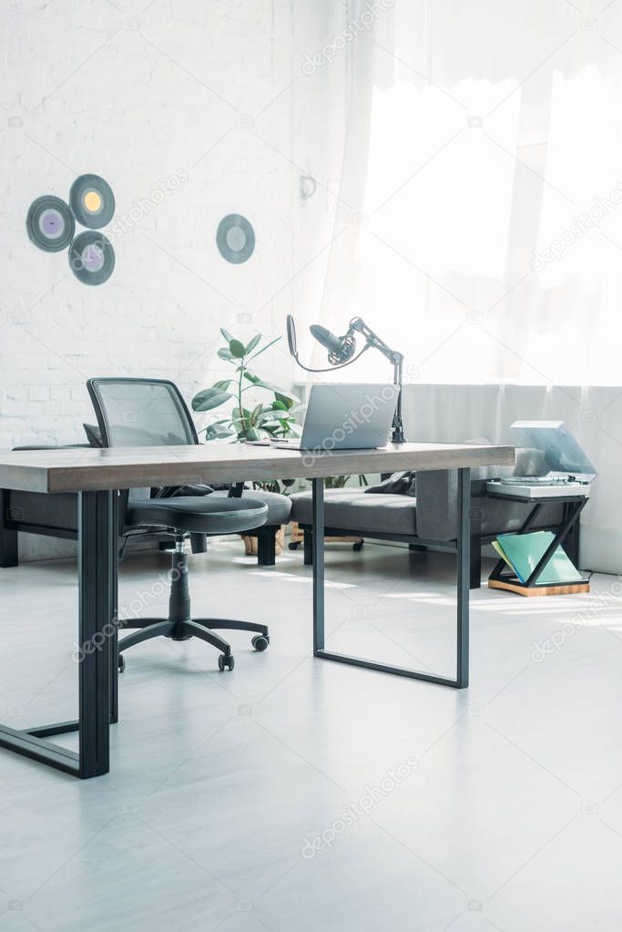 spacious, light broadcasting studio with laptop and microphone on table