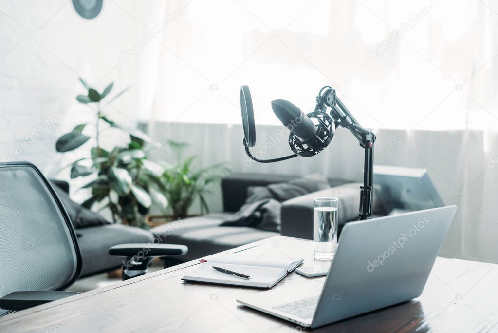 broadcasting studio with laptop and microphone on wooden desk