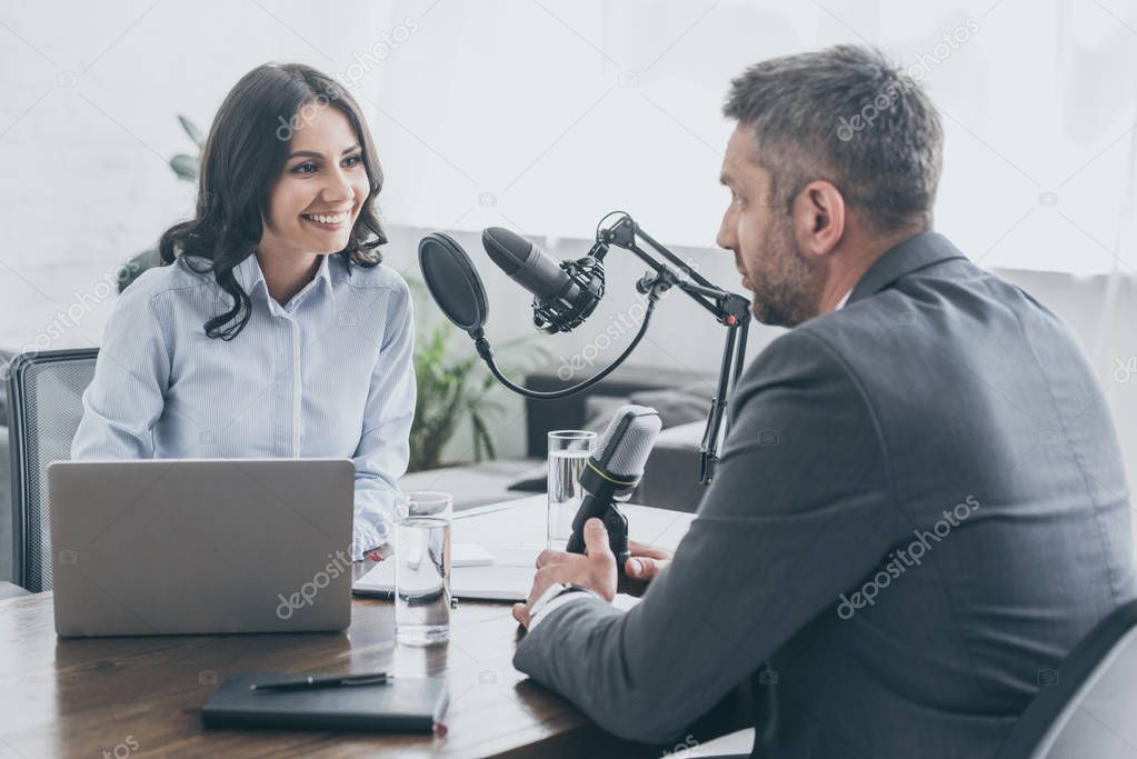 attractive smiling radio host interviewing businessman in radio studio