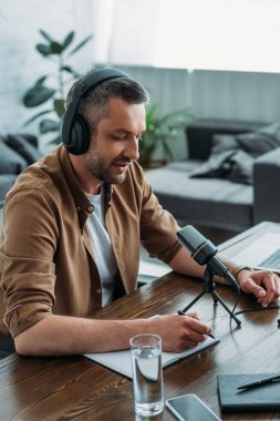 mikrofon yakınında işyerinde otururken dizüstü bilgisayar yazma kulaklık yakışıklı radyo host