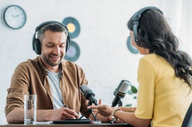 iş arkadaşı yanında işyerinde otururken dizüstü bilgisayar yazma kulaklık neşeli radyo host