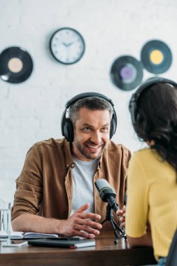işyerinde meslektaşıyla konuşurken gülümseyen radyo sunucusu gesturing
