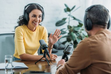 yayın stüdyosunda meslektaşıyla konuşurken gülümseyen radyo sunucusu gesturing