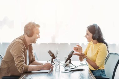 yayın stüdyosunda podcast kaydederken iki gülümseyen radyo hosts konuşma