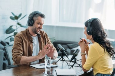 iş arkadaşı yanında işyerinde otururken hoşnutsuz radyo host gesturing