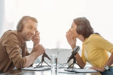 two cheerful radio hosts talking while recording podcast in radio studio clipart