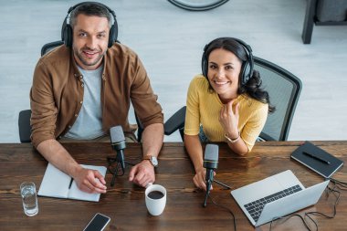 işyerinde oturan ve kamera gülümseyen kulaklık iki neşeli radyo hosts