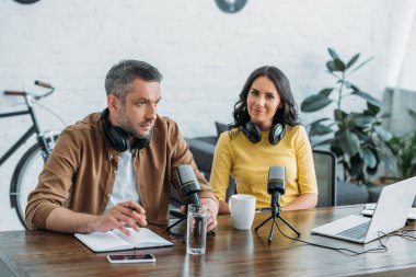 iş arkadaşı yanında işyerinde otururken kameraya bakarak güzel radyo host