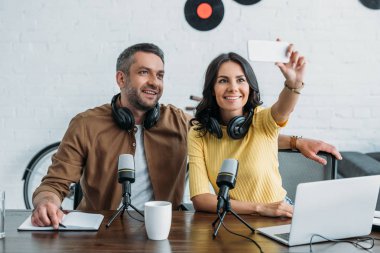 güzel radyo host yakışıklı meslektaşının yanında oturan ve akıllı telefon ile selfie alarak