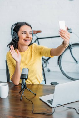 akıllı telefonda görüntülü sohbet yaparken neşeli radyo sunucusu el sallayarak