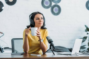 dalgın radyo host işyerinde otururken ve kahve fincanı tutarak uzağa bakıyor
