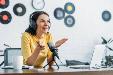 yayın stüdyosunda podcast kaydederken gülümseyen radyo sunucusu gesturing