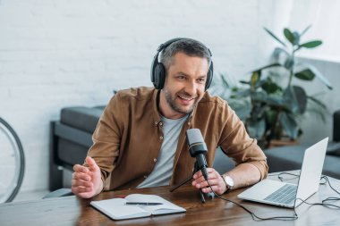 yakışıklı radyo sunucusu yayın stüdyosunda mikrofon konuşurken gülümseyen