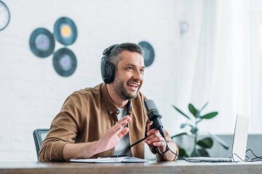 yayın stüdyosunda podcast kaydederken neşeli radyo sunucusu gesturing