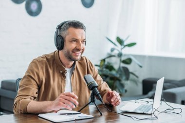 yayın stüdyosunda podcast kayıt kulaklık gülümseyen radyo host