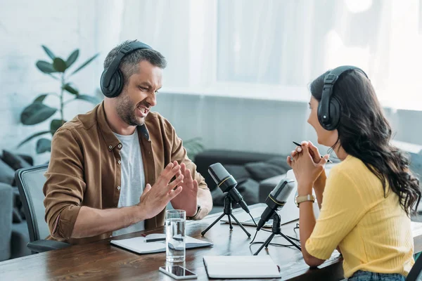 Gesto Anfitrião Rádio Descontente Enquanto Sentado Local Trabalho Perto Colega — Fotografia de Stock