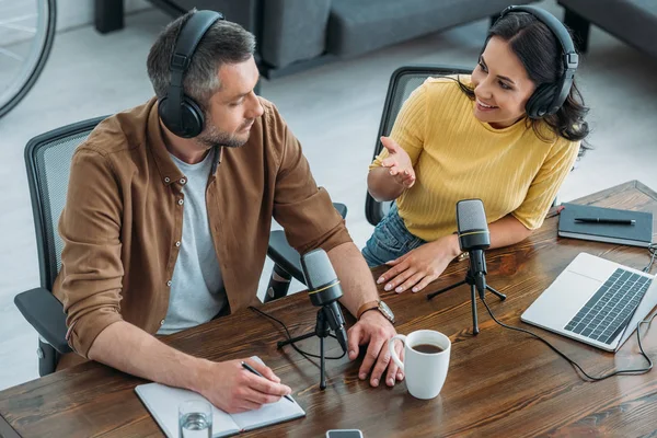 Cheerful Radio Host Talking Colleague While Sitting Wooden Table Microphones — Stock Photo, Image